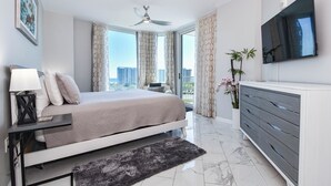 A modern bedroom with a bed, bedside table, and a large window with curtains.