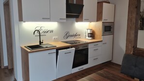 Una cocina moderna con armarios blancos, encimera de madera, cafetera y lavavajillas.