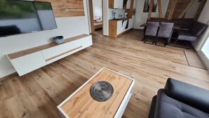 Una sala de estar moderna con una televisión de pantalla plana, piso de madera, una mesa de centro y un sofá.