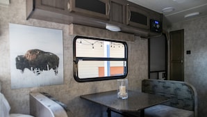 A compact RV interior with a kitchenette, a dining area, and a seating space. - Charming Winnie Drop Trailer with Cozy Private Patio Escape (Farmington)