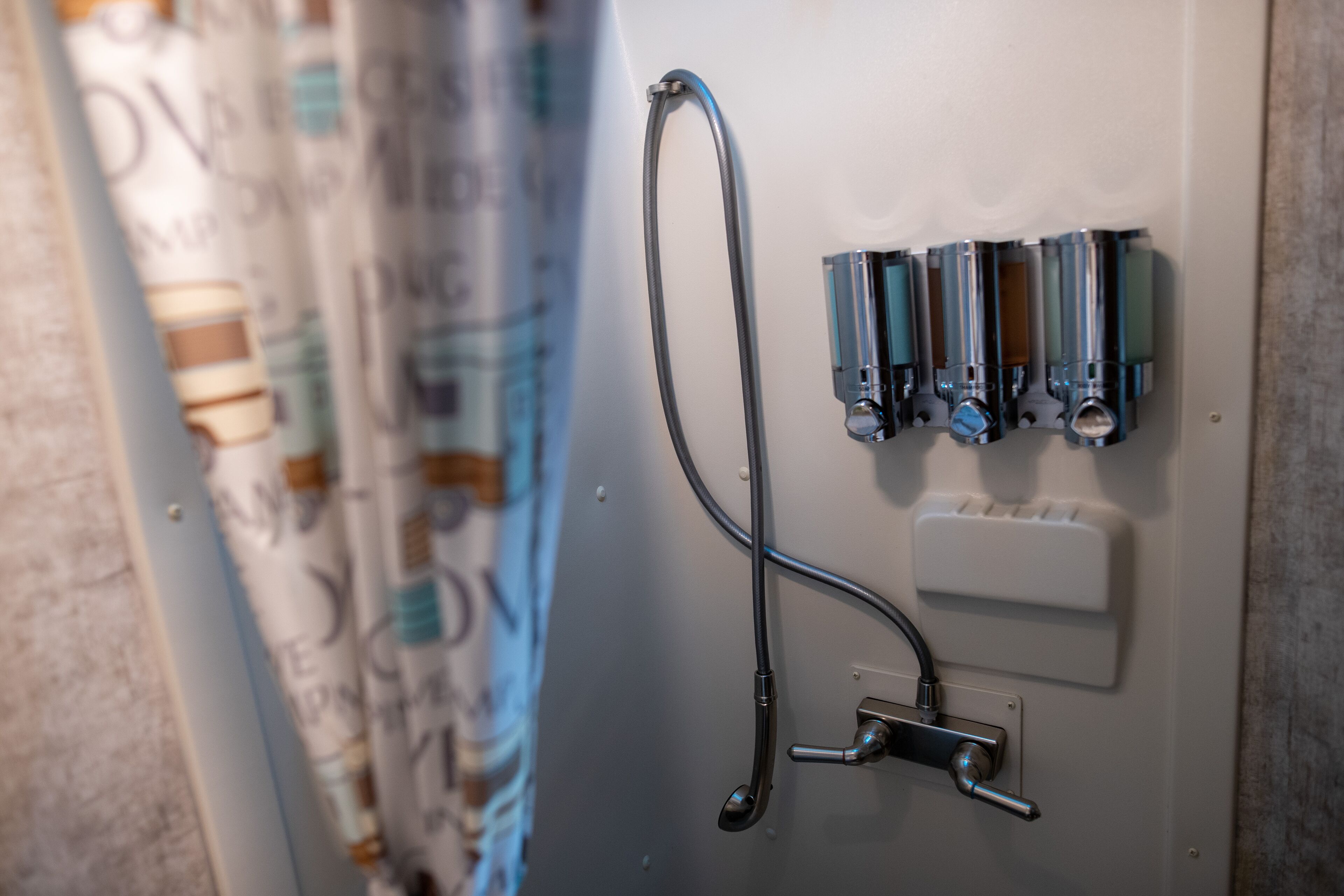 En duschpanel med flera kranar och ett handhållet duschmunstycke.