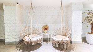 Una habitación con dos sillones colgantes, una mesita con un florero y una planta en maceta.