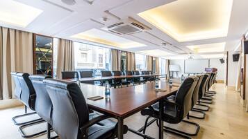 A conference room with a long table, multiple chairs, and large windows.