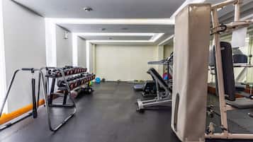 Un gimnasio con equipo de ejercicio, un espejo y un estante con mancuernas.
