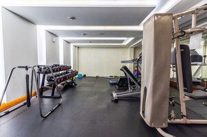 Un gimnasio con equipo de ejercicio, un espejo y un estante con mancuernas.