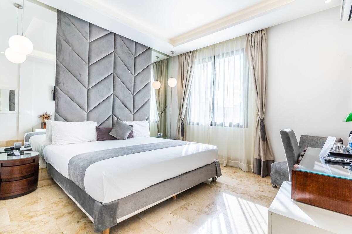 Un moderno cuarto de hotel con una cama grande, un escritorio y vistas a la ciudad.