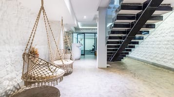 A modern interior with a staircase, hanging chairs, and a reception area.