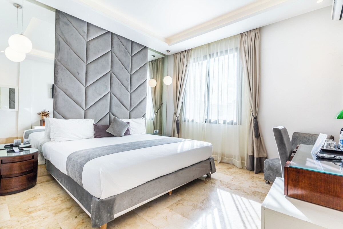 Un moderno cuarto de hotel con una cama grande, un escritorio y vistas a la ciudad.