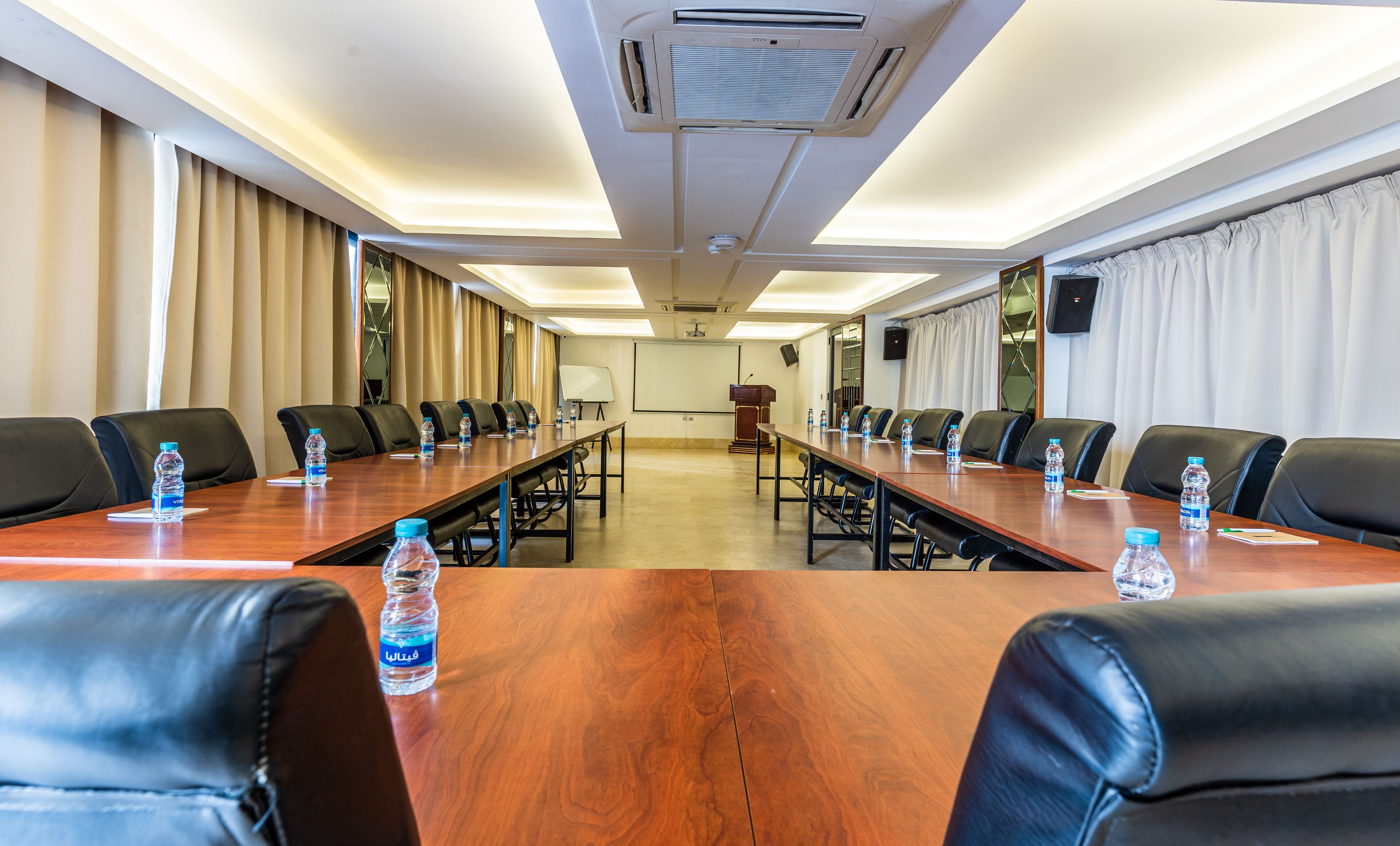 A conference room with a long table, black leather chairs, and water bottles on the table.