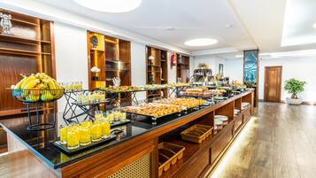 A buffet with various food items and beverages, wooden decor, and a potted plant.