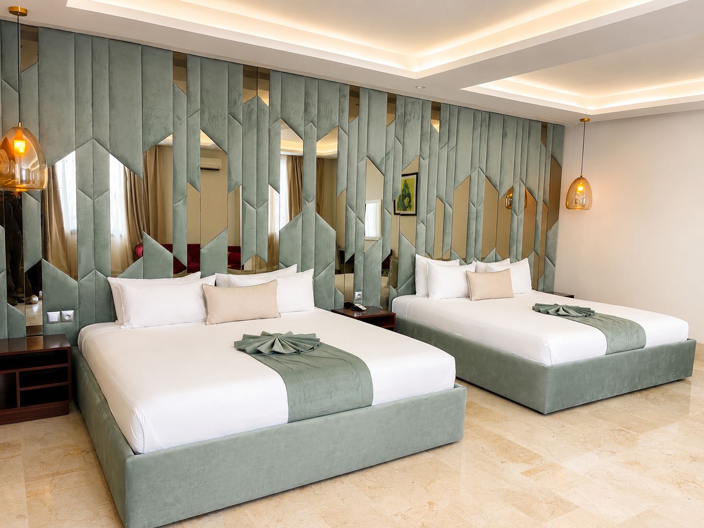 Une chambre d’hôtel avec deux lits, un mur miroir et un lustre moderne.