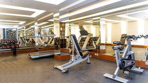 Un gimnasio moderno con diversos equipos de ejercicio, incluyendo cintas de correr y máquinas de pesas, y una amplia pared de espejos.