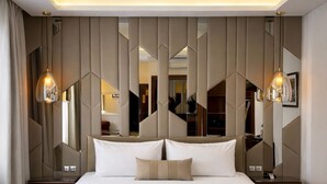 Un dormitorio moderno con una cama grande, paneles geométricos en la pared e iluminación colgante.