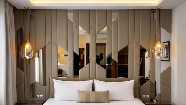 A modern bedroom with a large bed, geometric wall paneling, and pendant lighting. - One hotel Casablanca (Casablanca)