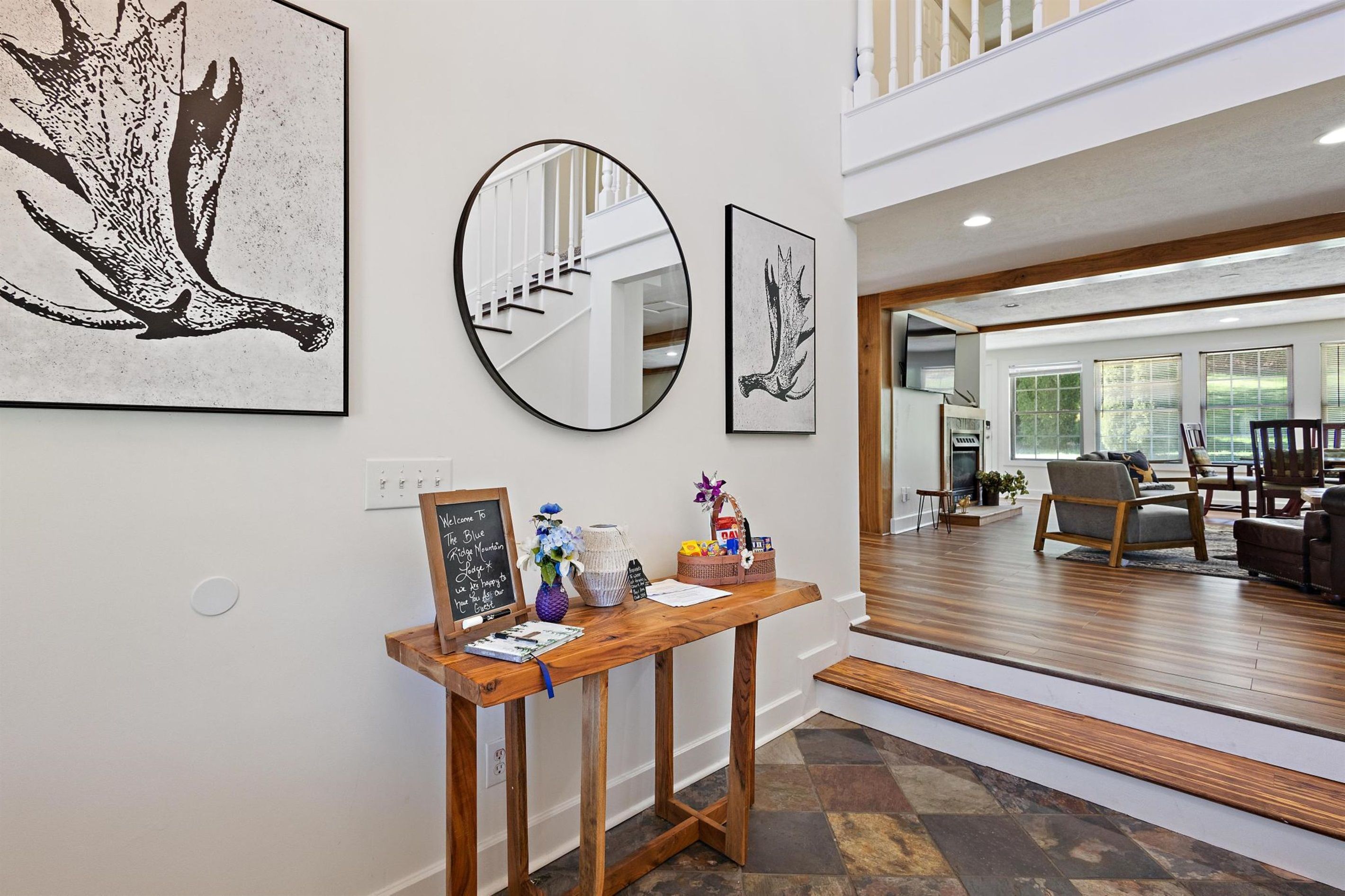 A reception area with a wooden console table, framed artwork, a mirror, and a chalkboard sign.