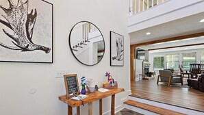 A modern living room with a wooden coffee table, a staircase leading upstairs, and artwork on the walls.