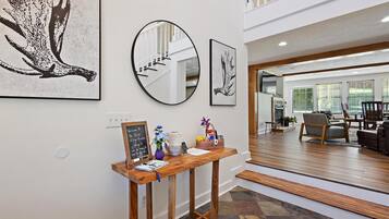 A reception area with a wooden console table, framed artwork, a mirror, and a chalkboard sign.