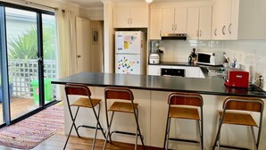 Een keuken met een centraal eiland, witte kasten, een koelkast, een magnetron en een rode toaster.