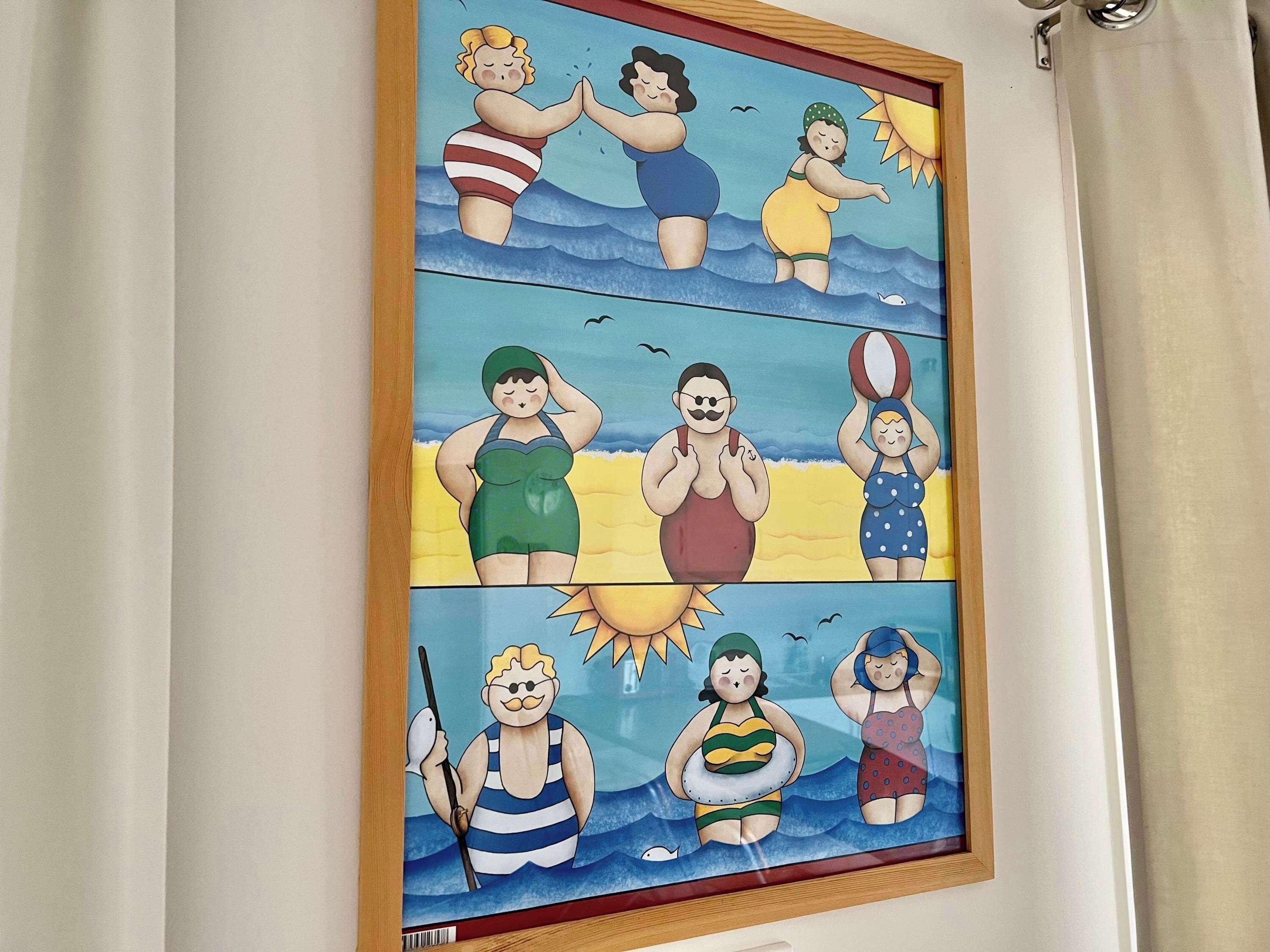 Una obra d'art emmarcada que representa diverses persones amb banyador a la platja.