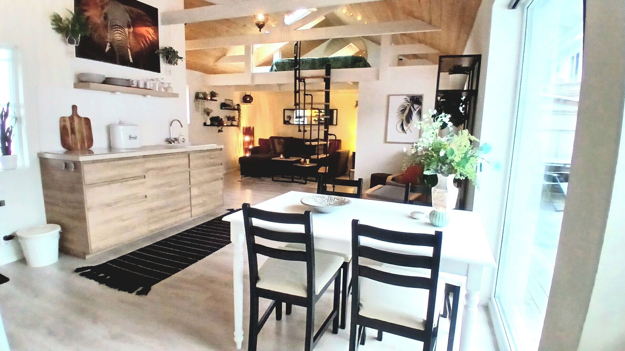 Una cucina moderna con isola centrale, zona pranzo con due sedie e angolo living con divano e tavolino.