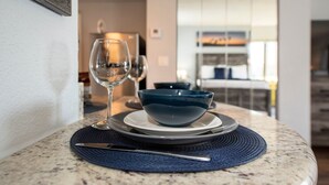 A dining area with a table set for two, featuring a dark blue bowl and wine glasses. - The Enclave Hotel and Suites (Orlando)