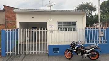 Um edifício com o número 551, entrada com portão e uma moto estacionada em frente.