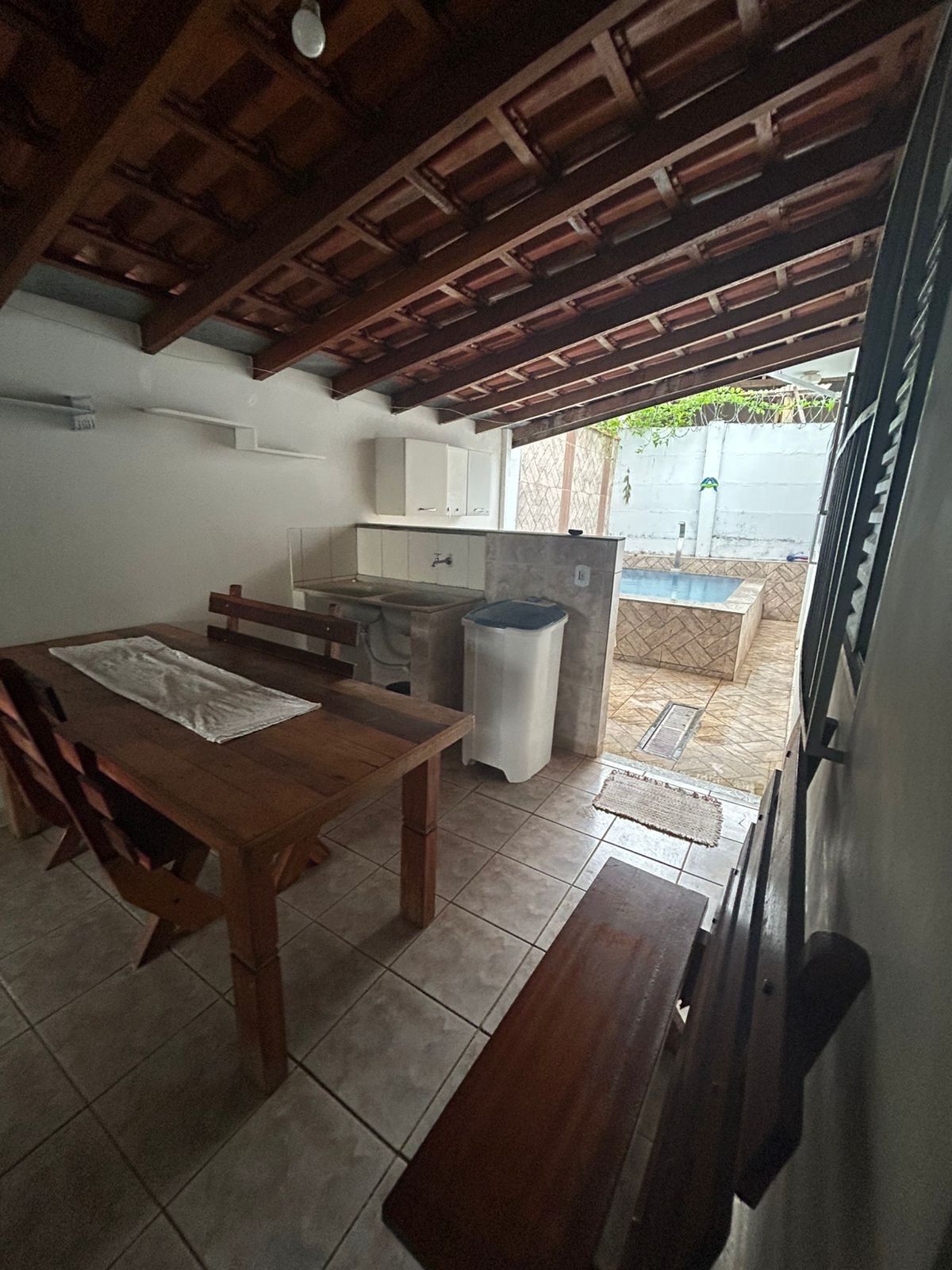 Uma cozinha compacta com uma mesa de madeira, um banco e uma pia.
