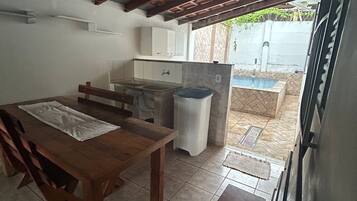 Uma cozinha compacta com uma mesa de madeira, um banco e uma pia.