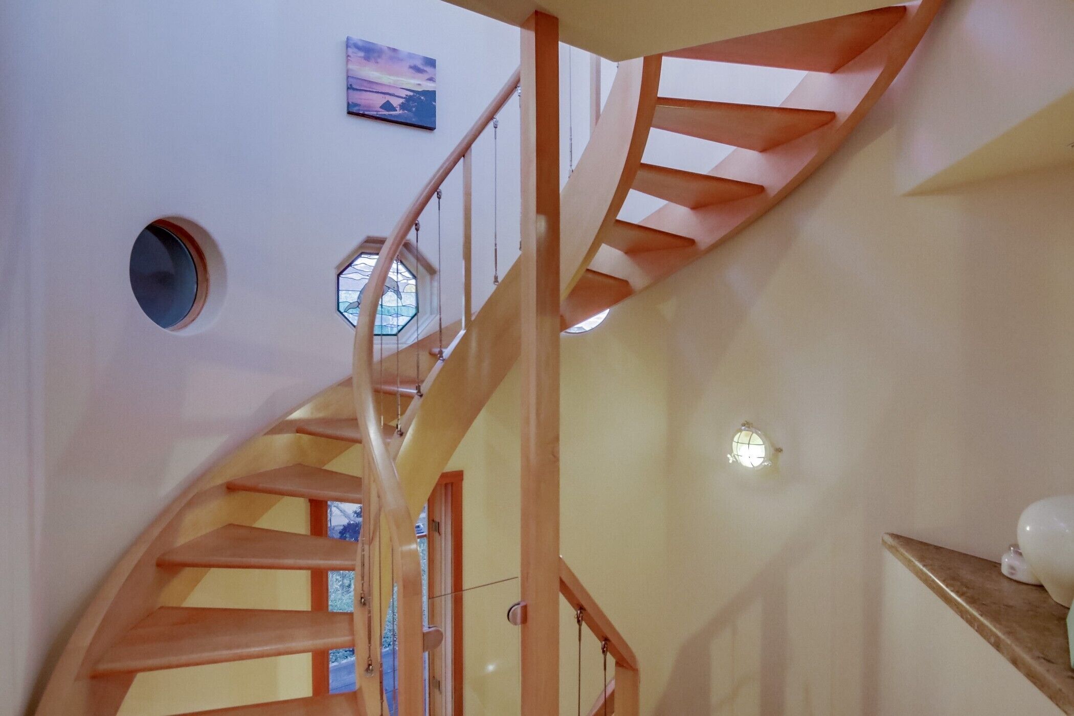 A spiral staircase with wooden railings and a round window.