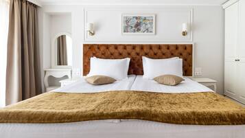 A hotel room with a large bed, two bedside tables, a headboard, and a painting on the wall.