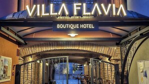 Der Eingang zum Villa Flavia Boutique Hotel mit einer Steinfassade, schmiedeeisernen Toren und einem Schild über dem Eingang.