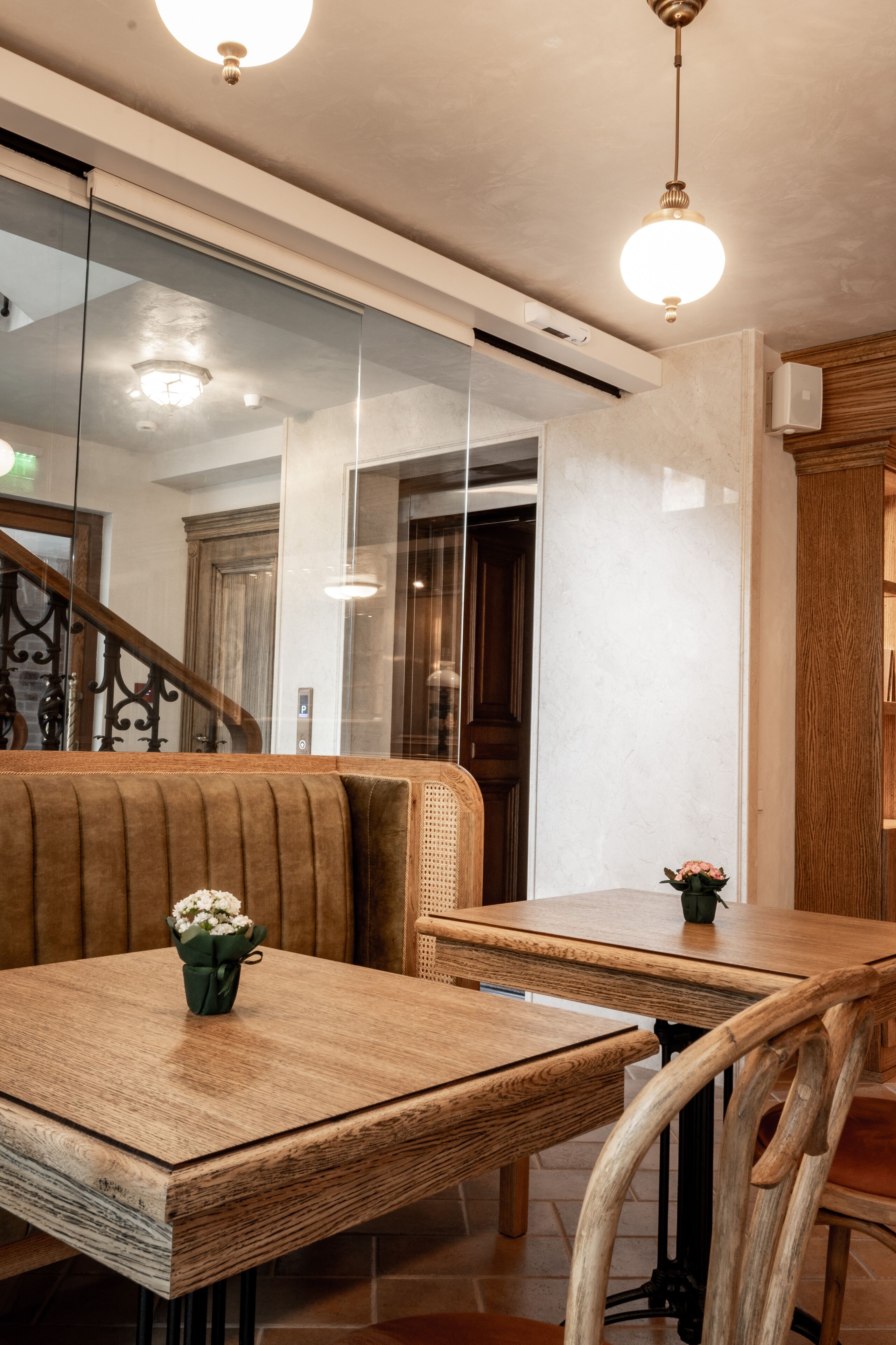 Una mesa de comedor de madera con un florero, un banco acolchado y una lámpara colgante.