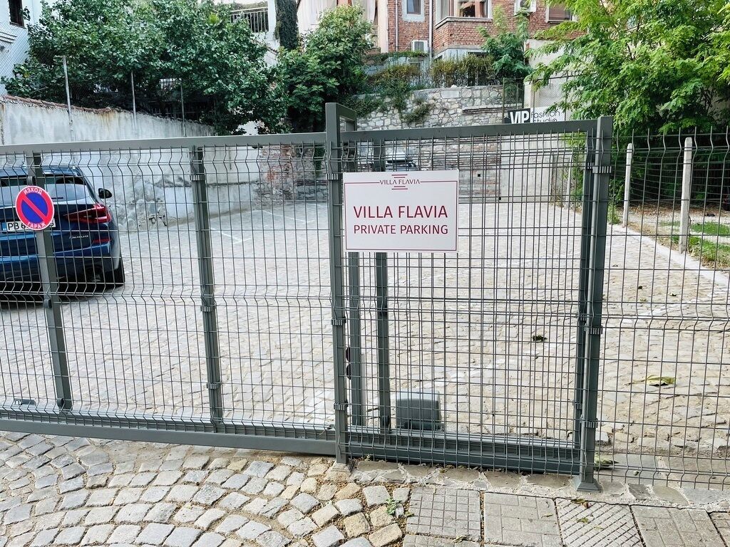 Un estacionamiento privado y vallado con un letrero que dice 'Villa Flavia Estacionamiento Privado'.