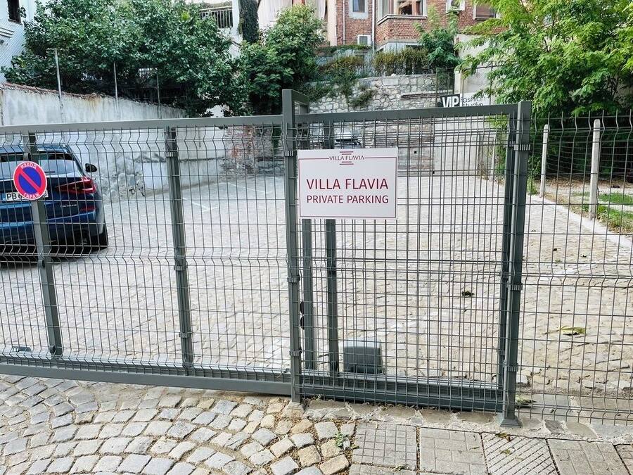 Un estacionamiento privado y vallado con un letrero que dice 'Villa Flavia Estacionamiento Privado'.