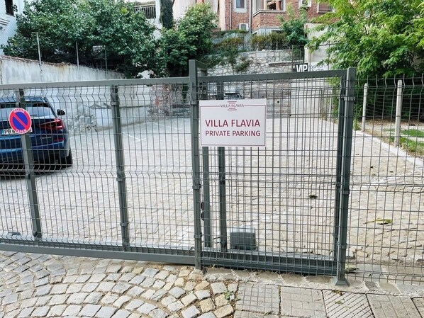 Un estacionamiento privado y vallado con un letrero que dice 'Villa Flavia Estacionamiento Privado'.