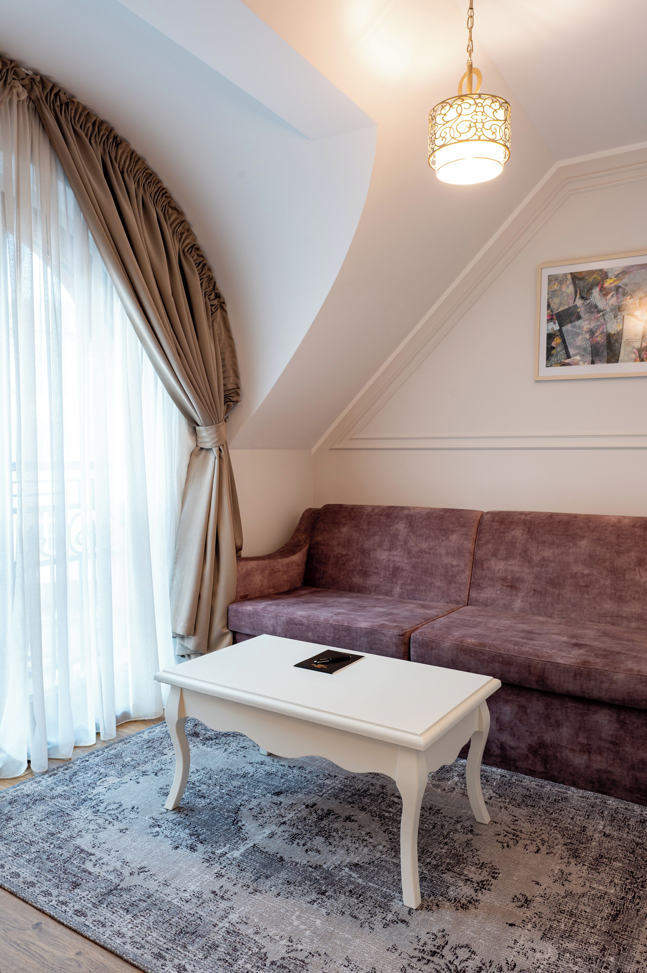 A room with a white table, a purple sofa, and a patterned rug.