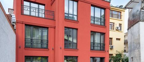 Un edificio rojo con varios balcones y ventanas amplias.