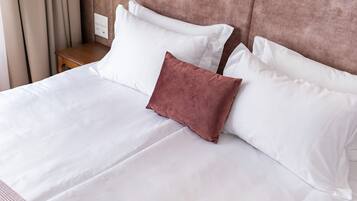Una cama bien hecha con sábanas blancas y una almohada marrón.