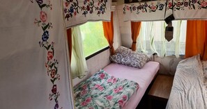 Cozy bedroom with a single bed, floral-patterned bedspread, and sheer curtains.