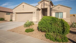 A residential house with a garage, a front door, and a well-maintained garden with shrubs and gravel. - Like New Home Private pool ,New furnishings, 20 mins to State Farm stadium  (Buckeye)
