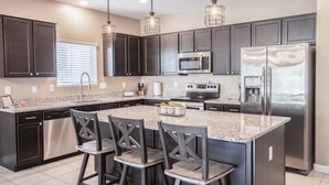 A modern kitchen with dark cabinets, stainless steel appliances, and a granite countertop. - Like New Home Private pool ,New furnishings, 20 mins to State Farm stadium  (Buckeye)
