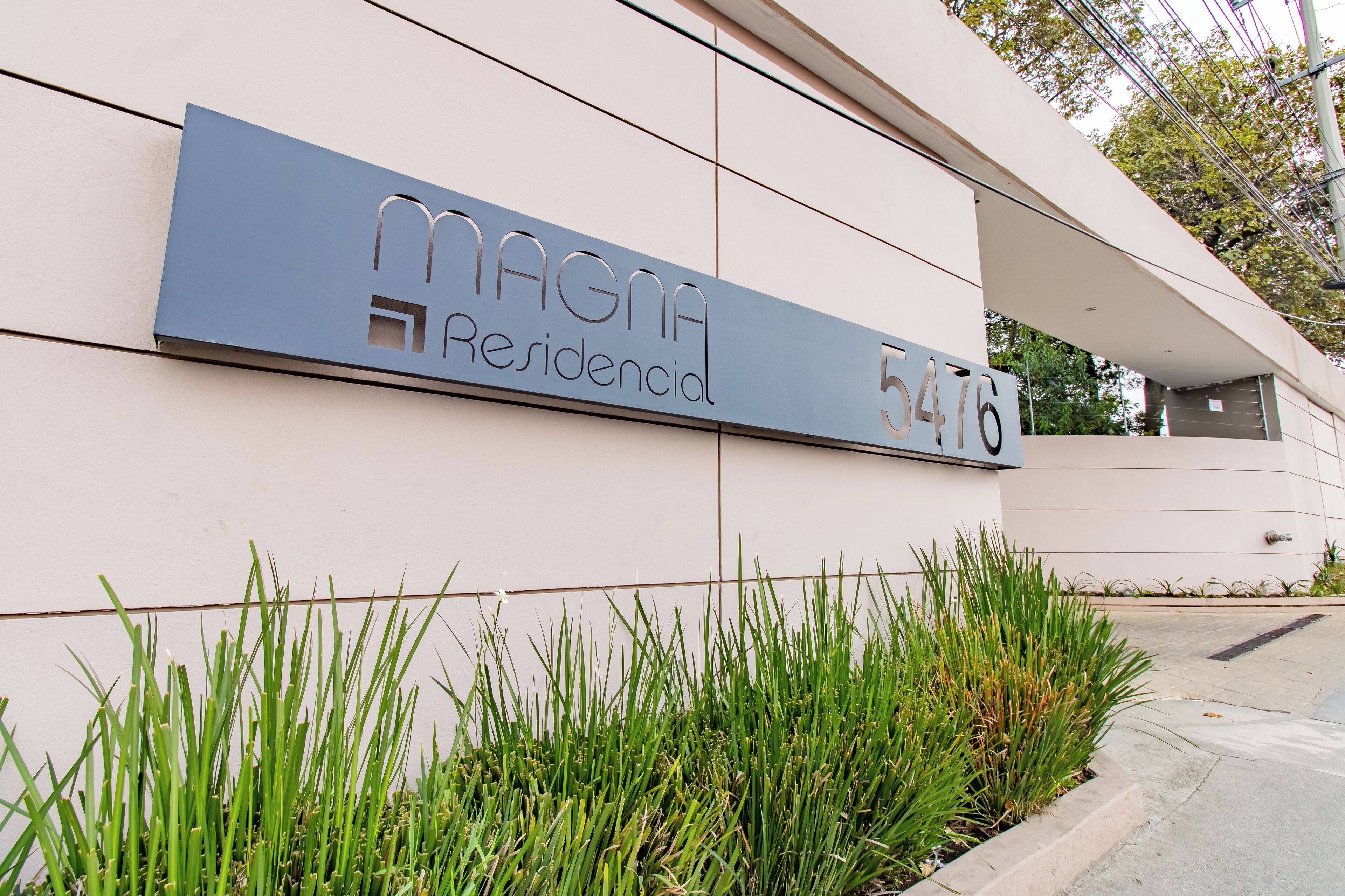 A modern building with a sign reading "MAGNA Residencial 5476".