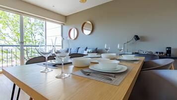 A modern dining area with a wooden table set for a meal, a sofa, and a balcony view.