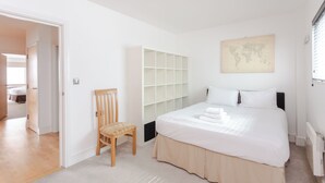 A bedroom with a bed, a chair, a wardrobe, and a world map on the wall. - Cosy and Spacious 3 BD flat on Bermondsey St (London)