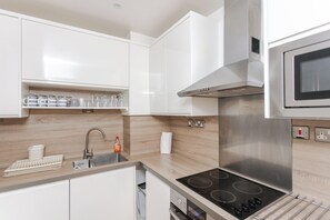 Cozinha moderna com armários brancos, exaustor de aço inoxidável e forno embutido.