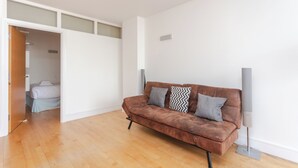 Un salon moderne avec un canapé en cuir marron, un téléviseur à écran plat et un plancher en bois.