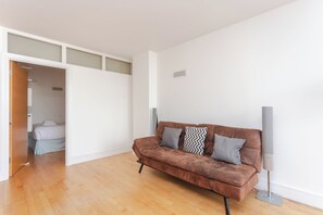 Un salon moderne avec un canapé en cuir marron, un téléviseur à écran plat et un plancher en bois.