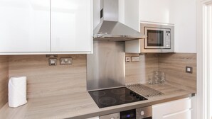 Une cuisine moderne équipée d’appareils électroménagers en acier inoxydable, notamment un four à micro-ondes et une cuisinière avec hotte aspirante.