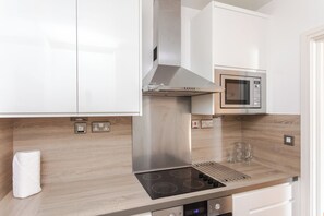 Une cuisine moderne équipée d’appareils électroménagers en acier inoxydable, notamment un four à micro-ondes et une cuisinière avec hotte aspirante.