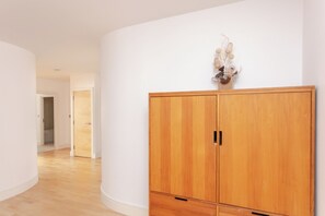 Un couloir avec une armoire en bois, un mur blanc et une porte donnant sur une autre pièce.